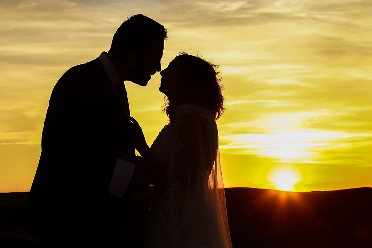 Silueta de la pareja a punto de besarse frente al sol poniéndose en el horizonte